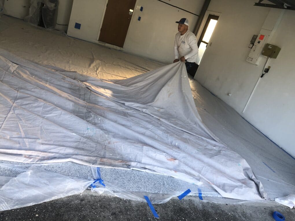 Residential Garage Repaint In Palm Harbor FL, Staff Preparing Floor To Protect From Paint
