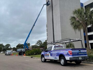 Workers On A Man Lift Pressure Washing A Commercial Building In Clearwater Florida