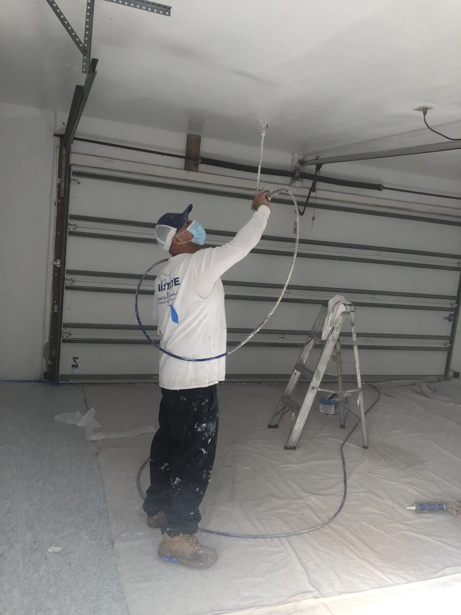 Painter Using Spray Gun To Paint Garage Ceiling In Palm Harbor Florida